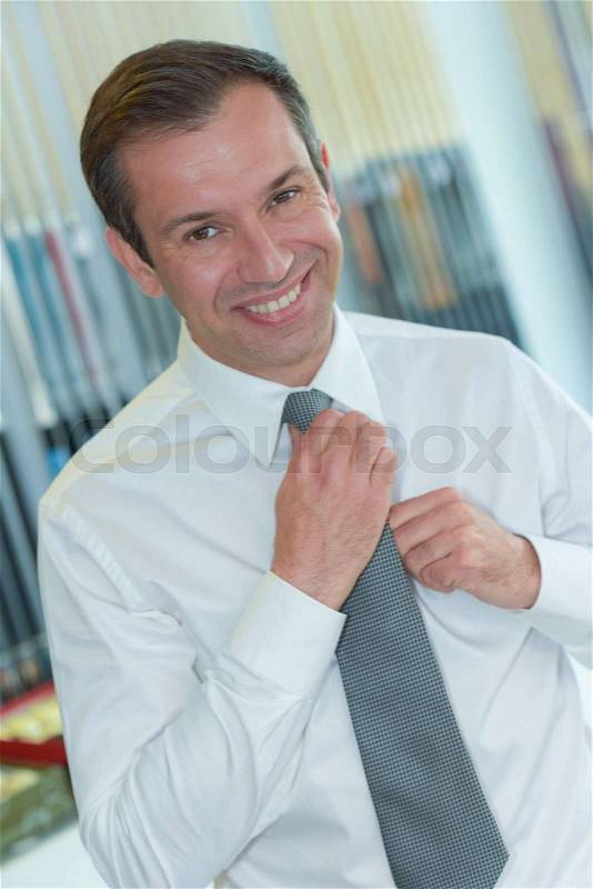 Portrait of man straightening his tie, stock photo