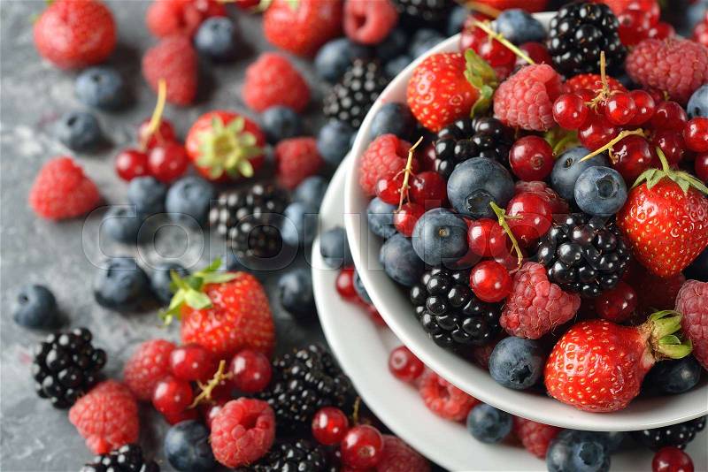 Salad of fresh forest berries on a gray background, stock photo