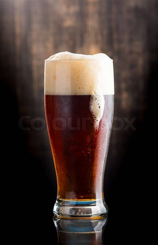 Glass of dark beer over on dark wooden background, stock photo
