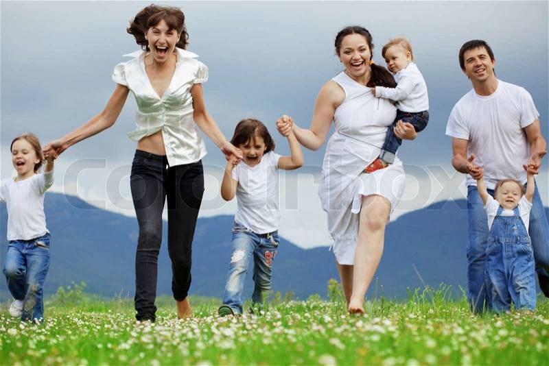 Group of happy parents with children running in field, stock photo
