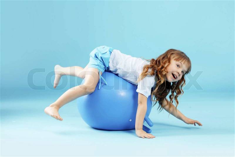 Child with gymnastic ball on bleu studio background, stock photo