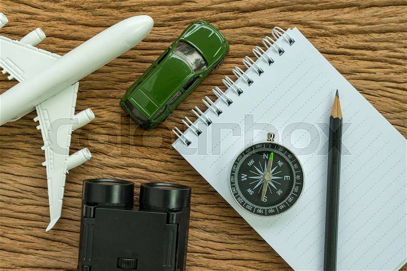Travel planning road trip concept with airplane, compass, binoculars, pencil, paper note and miniature car on wood table, stock photo