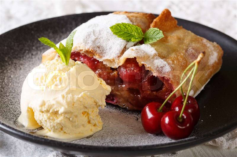 Juicy cherry strudel with vanilla ice cream and mint closeup on a plate. horizontal , stock photo
