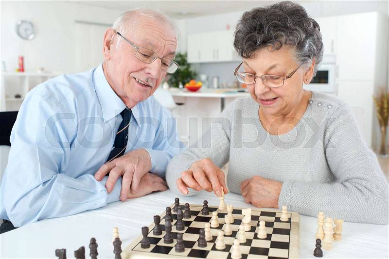 Elderly couple playing chess, stock photo