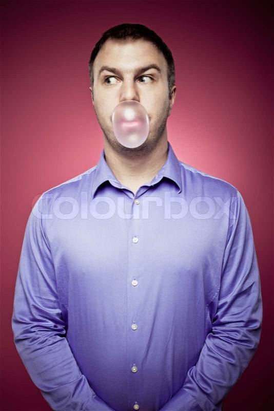 Young man making a chewing gum bubble and looking left, stock photo