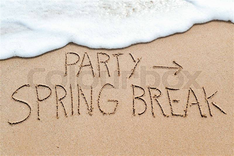 Closeup of an arrow sign and the text party spring break written in the wet sand of the seashore, in a beach, stock photo