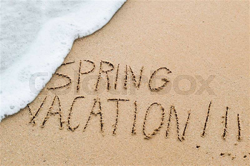 Closeup of the text spring vacation written in the sand of a beach, stock photo