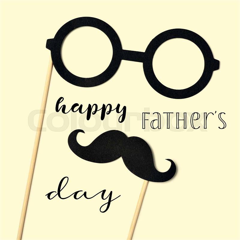 The text happy fathers day and a pair of round-framed eyeglasses and a mustache attached to handles depicting a man face, on a beige background, stock photo