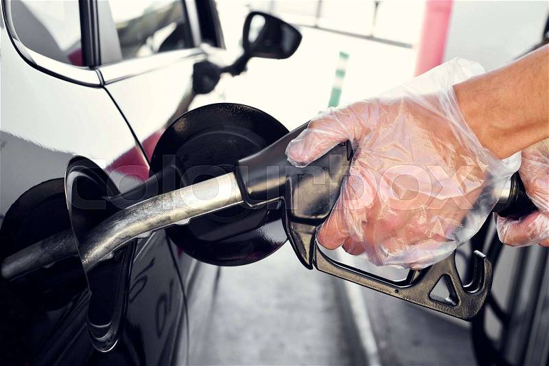 Closeup of a young caucasian man filling the fuel tank of a car, stock photo