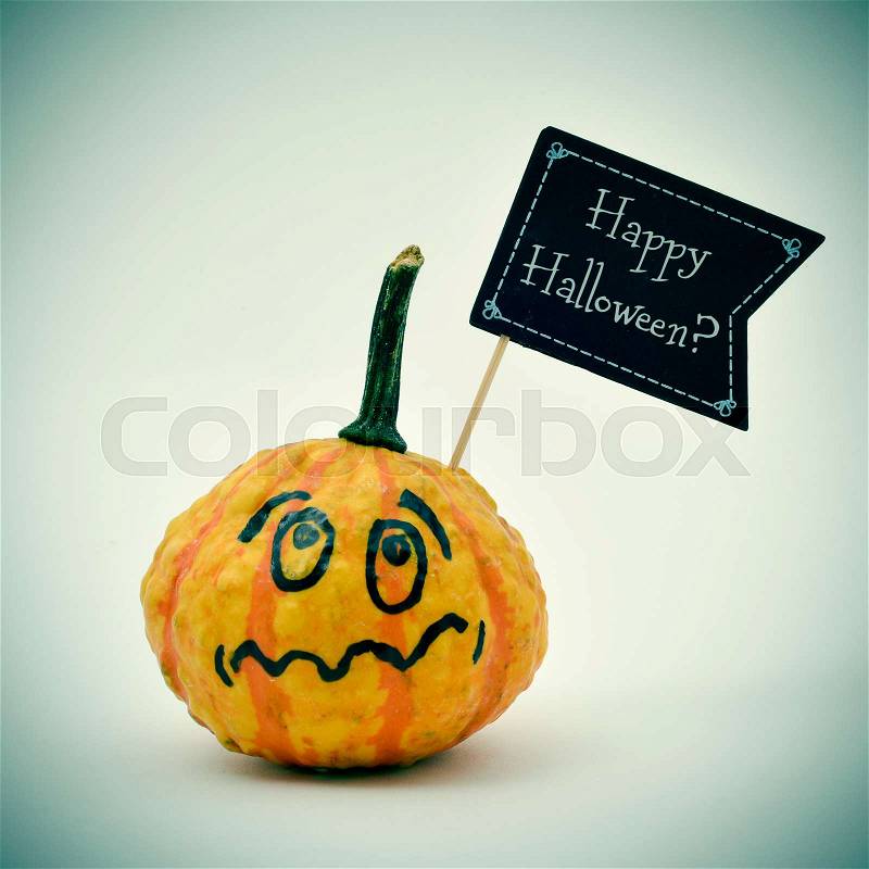 Closeup of a terrified pumpkin with a black flag-shaped signboard with the question Happy Halloween? written in it, against an off-white background, stock photo