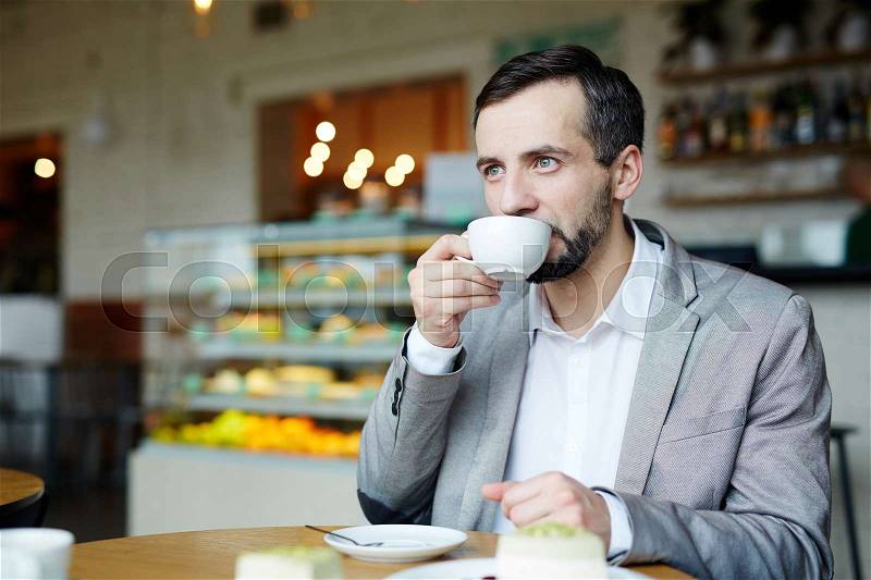 Businessman sitting in cafeteria and having tea or coffee, stock photo