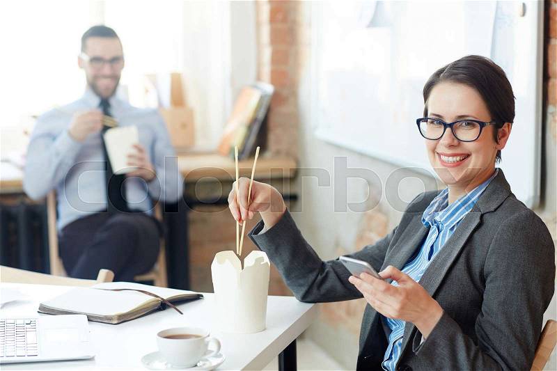 Happy businesswoman with chopsticks eating chinese food from take-out box, stock photo