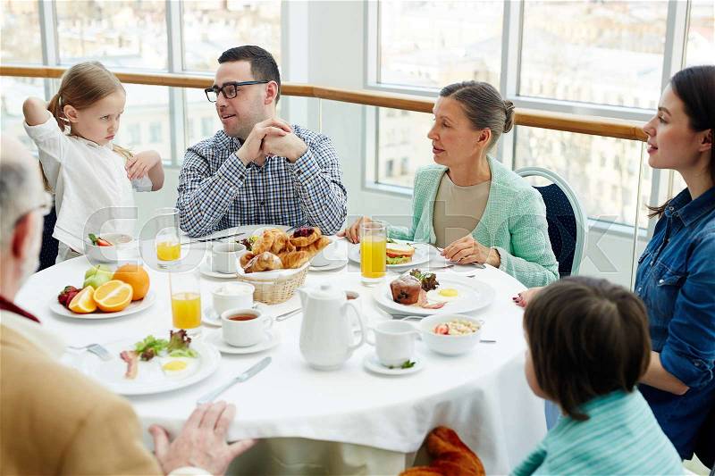 Big family having talk by breakfast in restaurant, stock photo