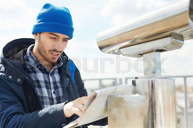 Young traveler looking at location map, stock photo