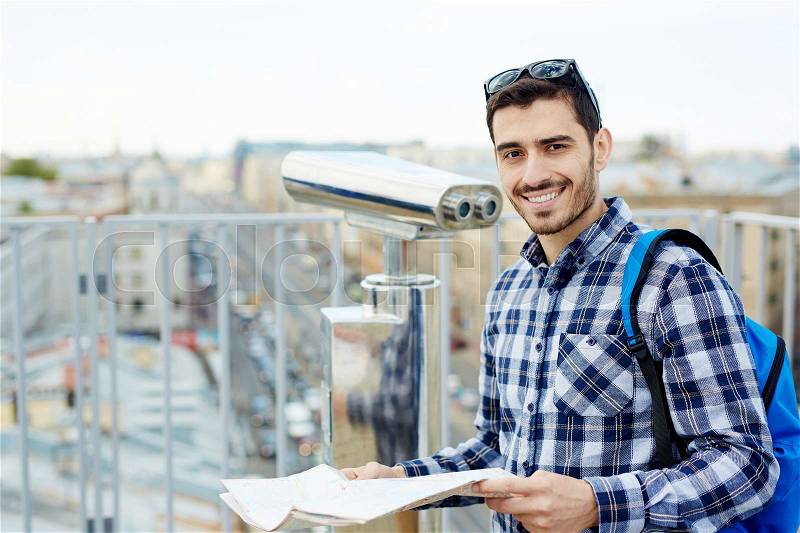 Happy young traveler looking at camera in urban environment, stock photo