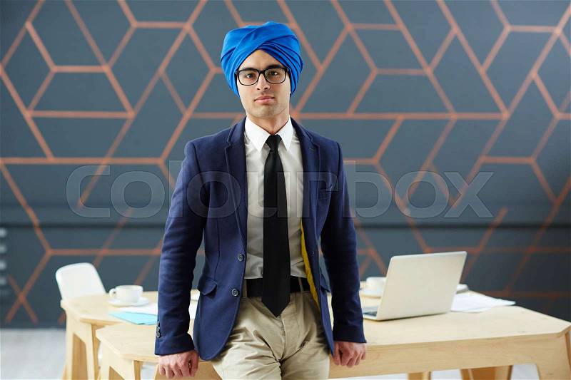 Handsome man in suit and blue turban looking at camera, stock photo