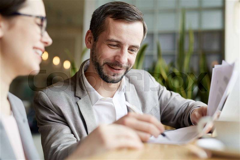 Happy man signing business document after negotiating, stock photo