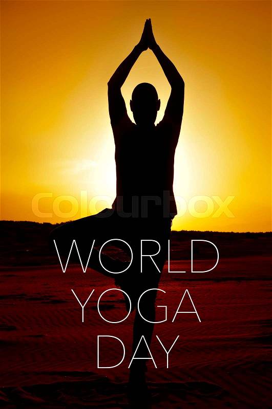 A young yogi man practicing the tree pose outdoors in backlight at sunset and the text world yoga day, stock photo