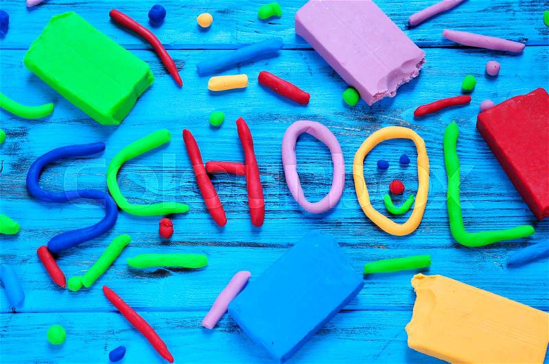 The word school written with modelling clay of different colors on a blue rustic wooden background, stock photo