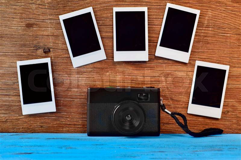 A retro camera and some blank instant photos attached to a rustic wooden surface, stock photo