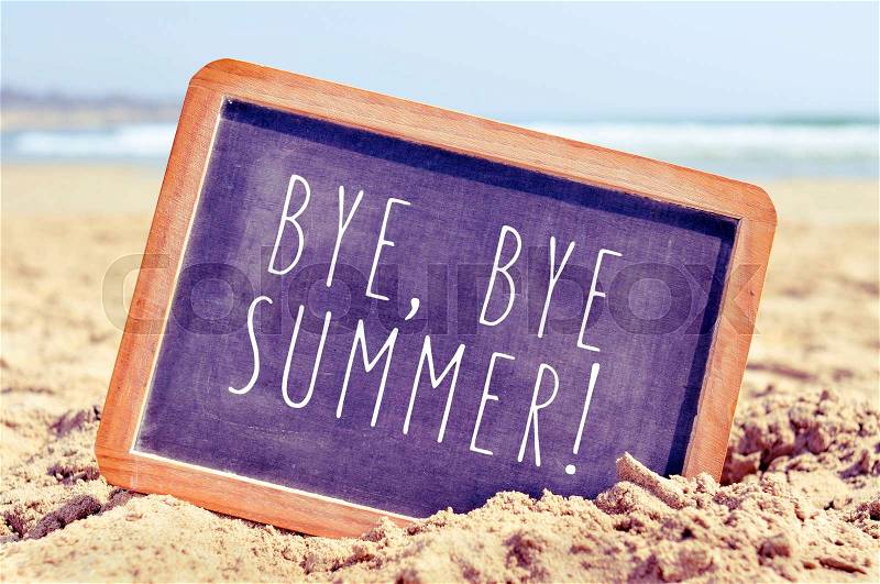 Closeup of a chalkboard with the text bye, bye summer written in it, on the sand of a beach, stock photo