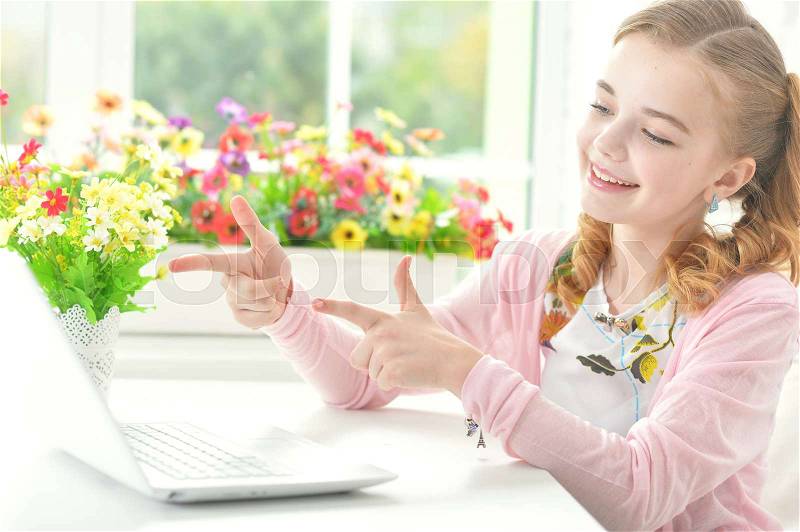 Cute little girl pointing to modern laptop, stock photo