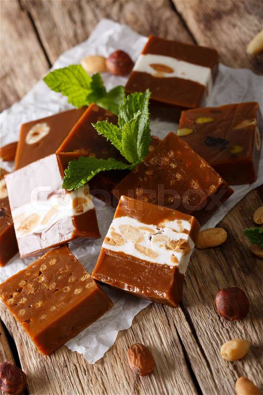 Delicious soft caramel candy with nuts close-up on parchment on the table. vertical , stock photo