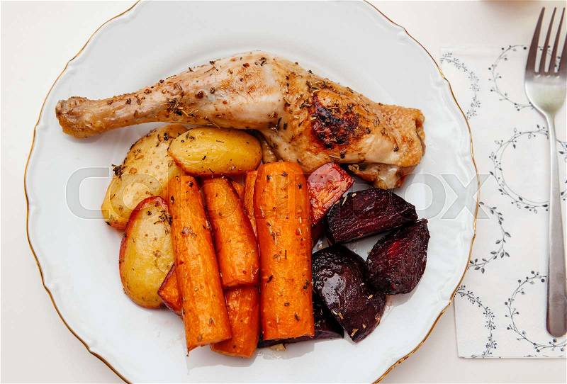 Delicious food in white plate - view from above - homemade food carrots, chicken, potatoes, and sugar beet ass seasoned with dried herbs, stock photo