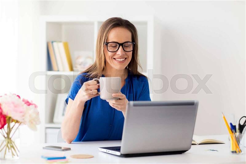 Business, freelance, people and technology concept - happy smiling woman with laptop computer drinking coffee at home or office, stock photo