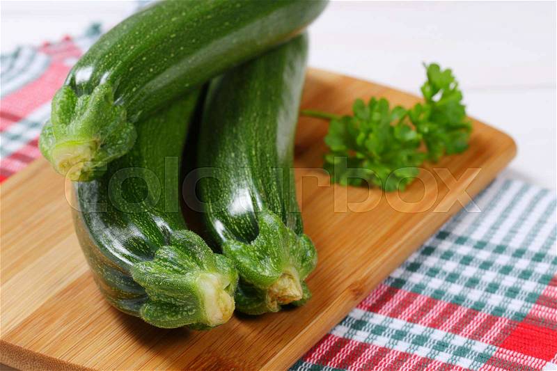 Fresh green zucchini on wooden cutting board - close up, stock photo