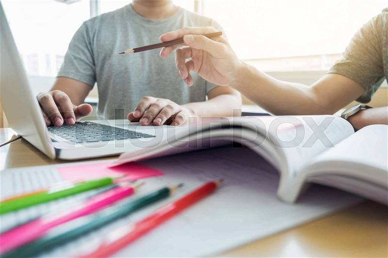 Teaching helping technology concept. Woman young teacher or tutor with adult students in classroom at desk with papers, laptop computer. Studies course, stock photo