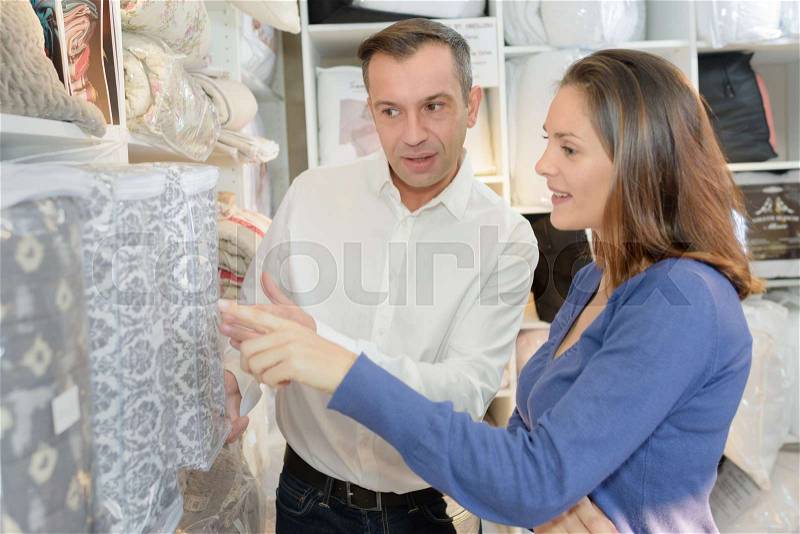 Happy couple in store choosing curtains for their new house, stock photo