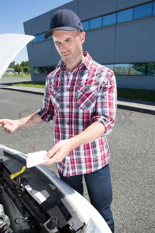 Young professional mechanic checks the oil in a car, stock photo