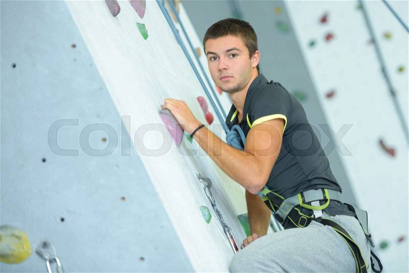 Sporty male climbing on an indoor climbing wall, stock photo