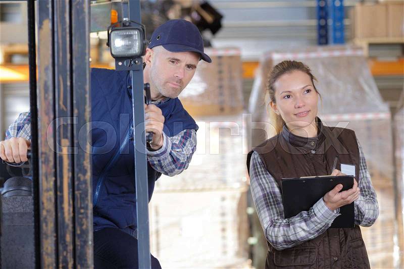 Worker and manager distributing goods in a warehouse, stock photo