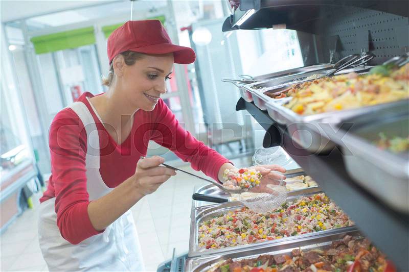 Buffet female worker servicing food in cafeteria, stock photo