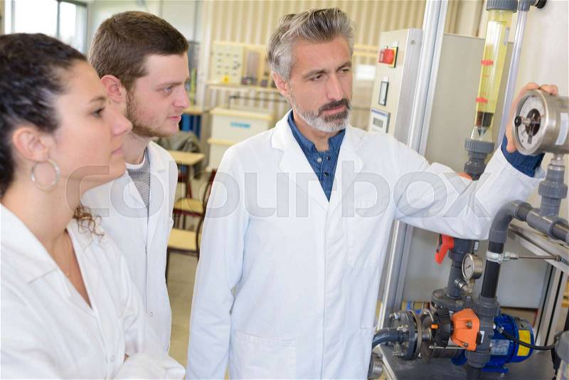 Young man and woman measuring heat pump temperature with teacher, stock photo
