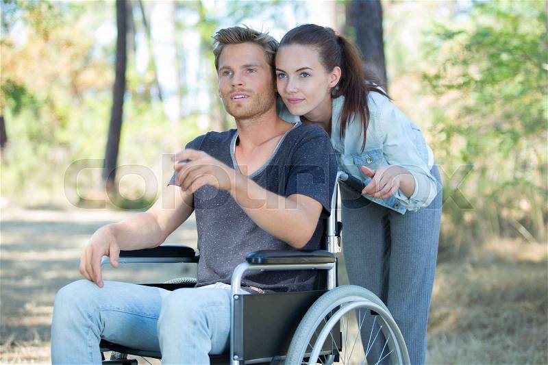 Handsome disabled man wandering in nature with his pretty girlfriend, stock photo