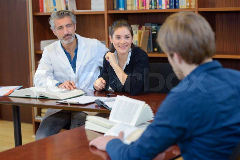 Medicine student taking final exam with panel of professionals, stock photo