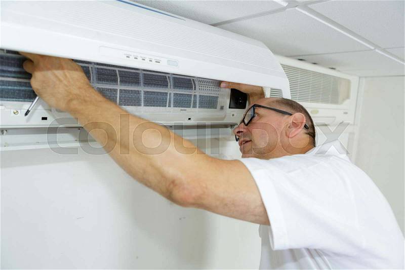 Mature technician cleaning air conditioning system, stock photo