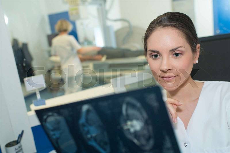 Female radiologist examining brain scan by mri machine, stock photo