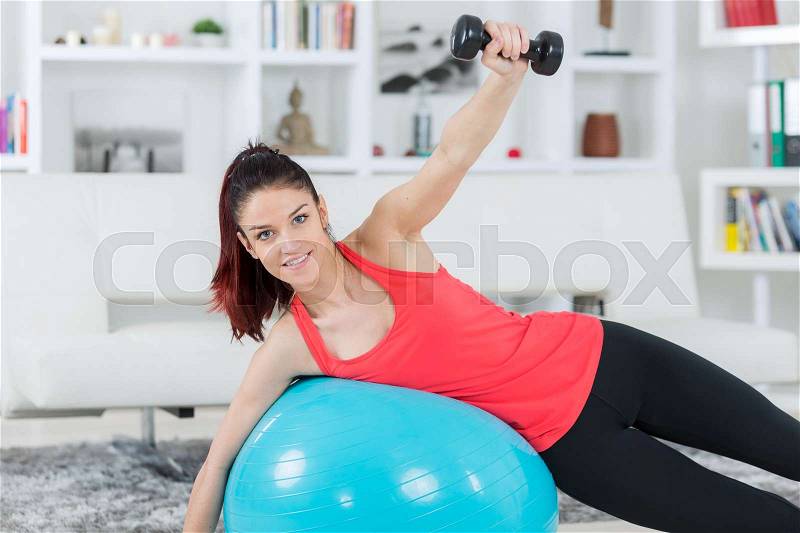 Young woman training at home staying fit, stock photo