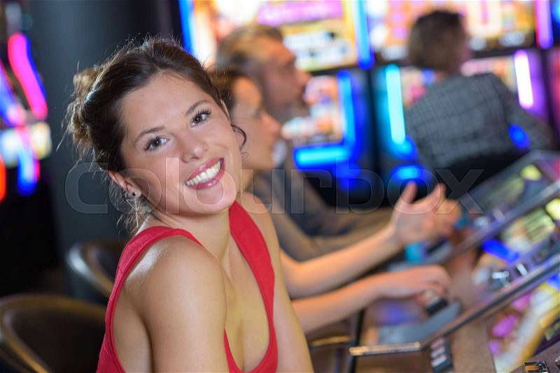 Beautiful woman in red dress playing slot machine, stock photo