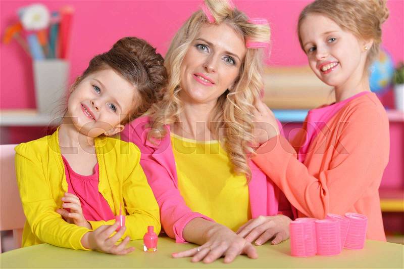 Two little girls doing manicure and hairstyle for their mother, stock photo