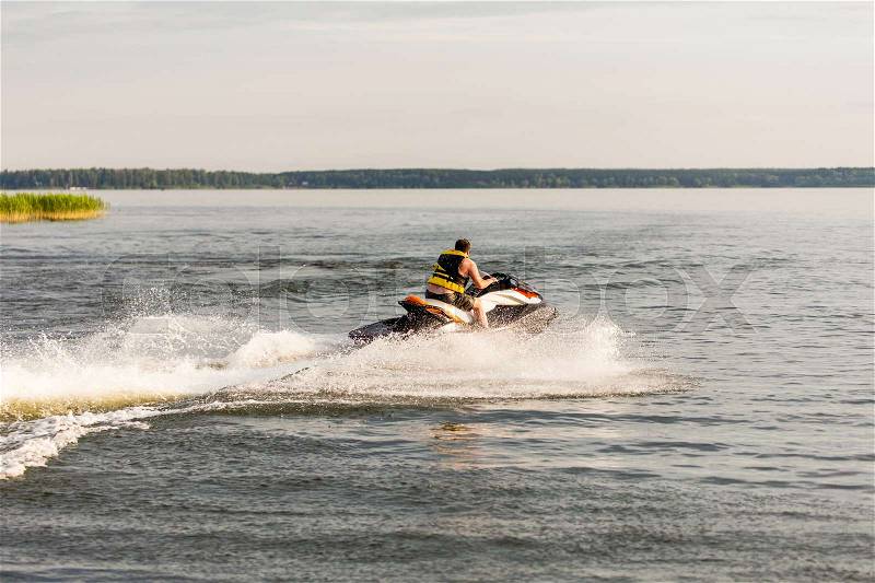 A man driving a jet ski , stunting and making spray of water drops, stock photo