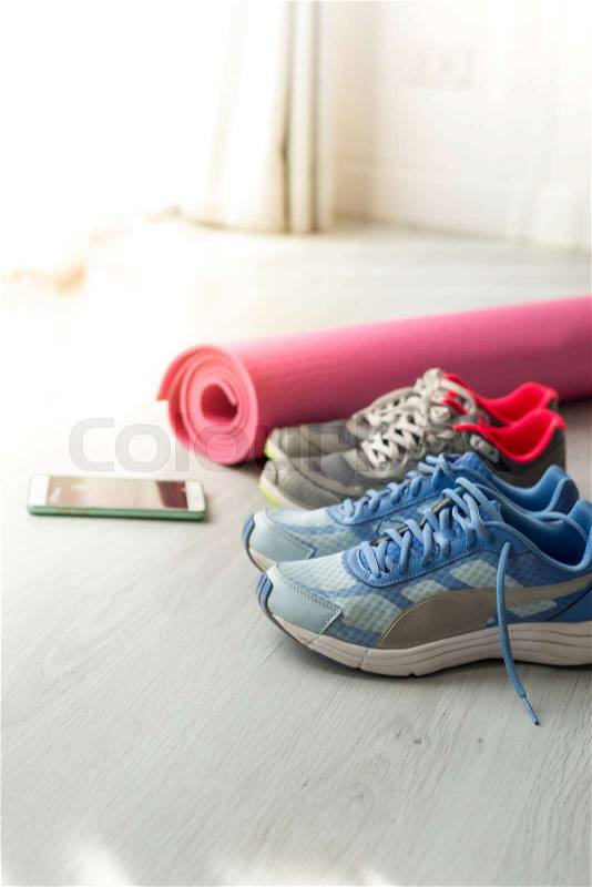 Dirty sport shoes on floor with yoga mat and smartphone at home. Lifestyle concept, stock photo