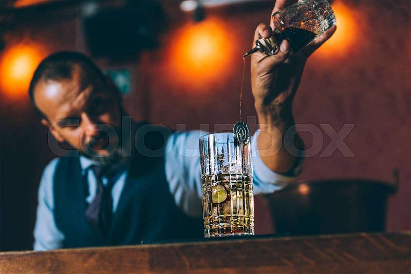 Expert barman is making cocktail at night club, stock photo