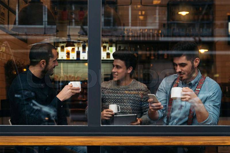 Friends drinking coffee and chatting in cafe, stock photo