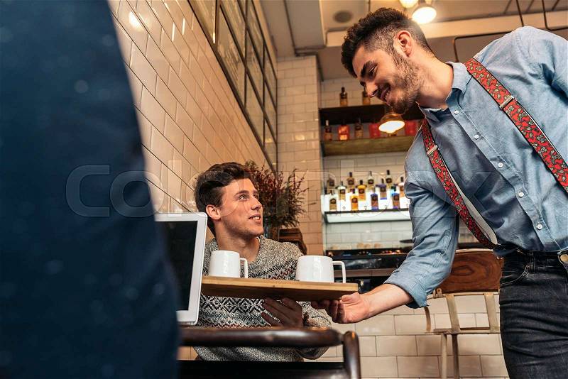 Waiter holding a tray with coffees in the bar, stock photo