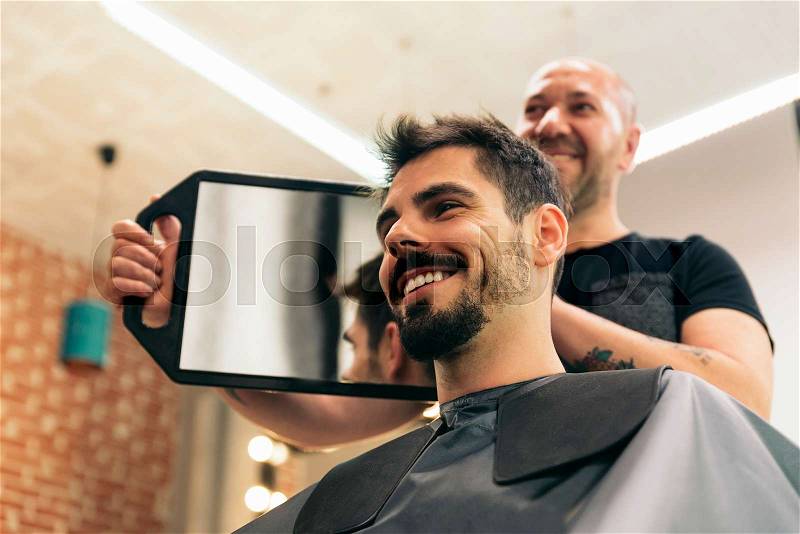 Hairdresser showing his work through the mirror, stock photo